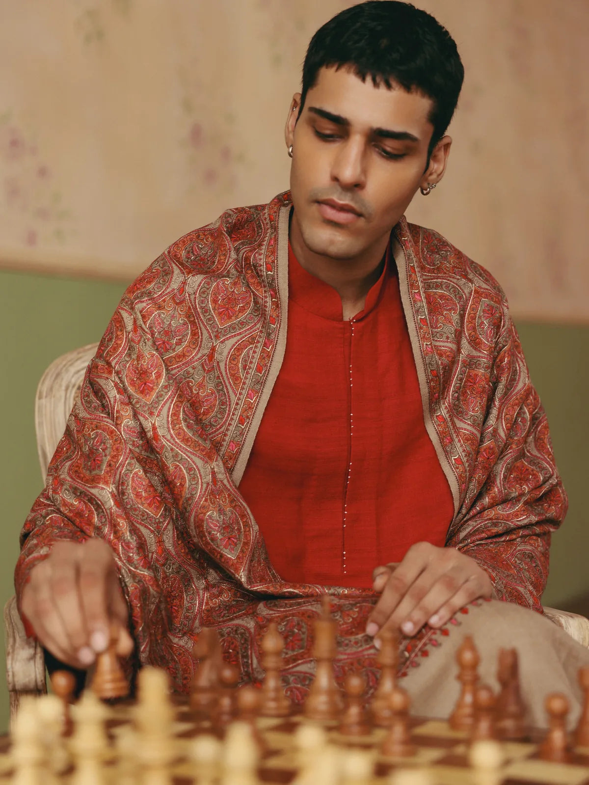 Man wearing a paisley Sozni shawl while playing chess